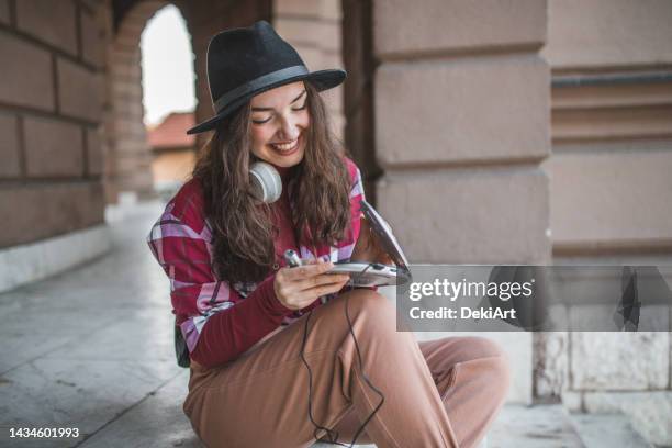 a happy young woman spends the day outdoors, listening to music via a mini disc player - personal compact disc player 個照片及圖片檔