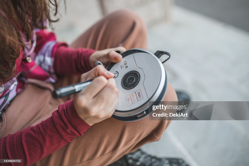 Close-up of a woman's hand writing the name of the CD on it
