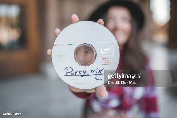 primer plano de un disco compacto con canciones de fiesta, sostenido por una mujer joven - compact disc fotografías e imágenes de stock