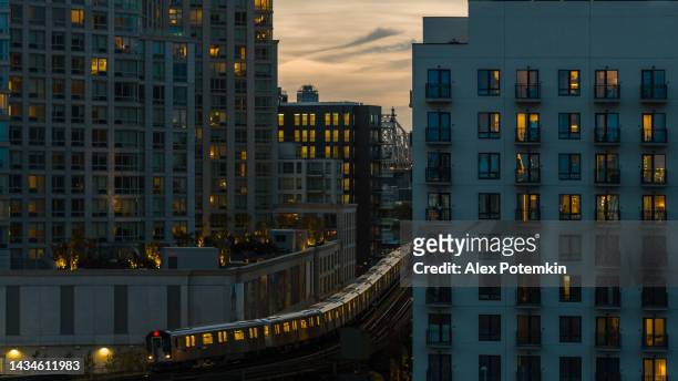 夕方、クイーンズ州ロングアイランドシティの建物間の高架地下鉄線に乗る電車。 - クイーンズボロ橋 ストックフォトと画像
