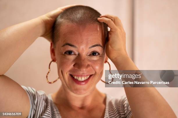 portrait of a woman with cancer touching her shaved hair - shaved head ストックフォトと画像