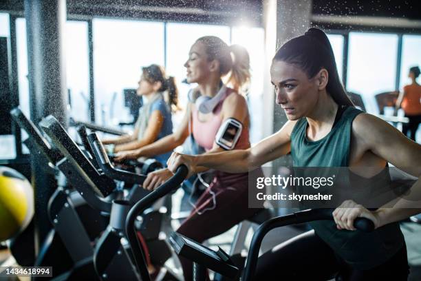 determined athletic woman having a stationary bike class in a gym. - spin class stock pictures, royalty-free photos & images