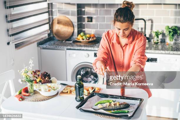 woman cooking fish at home. - cooking fish stock pictures, royalty-free photos & images