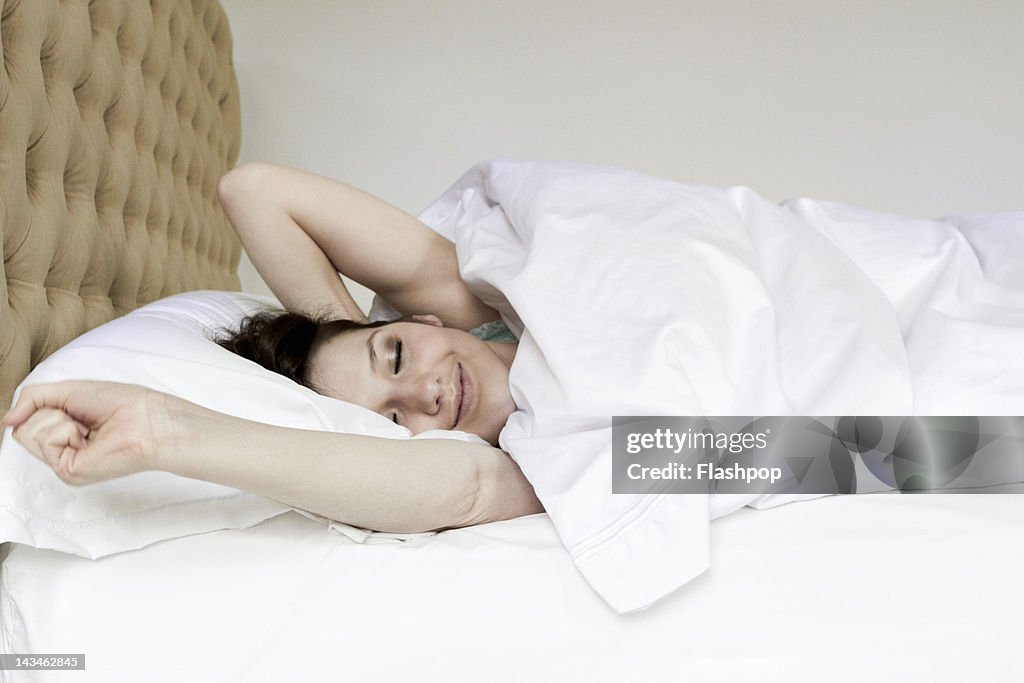Woman waking and stretching in bed