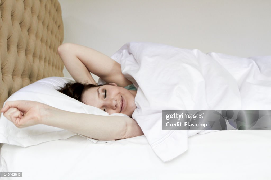 Woman waking and stretching in bed