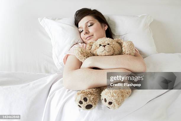 woman cuddling teddy bear in bed - teddy day stockfoto's en -beelden