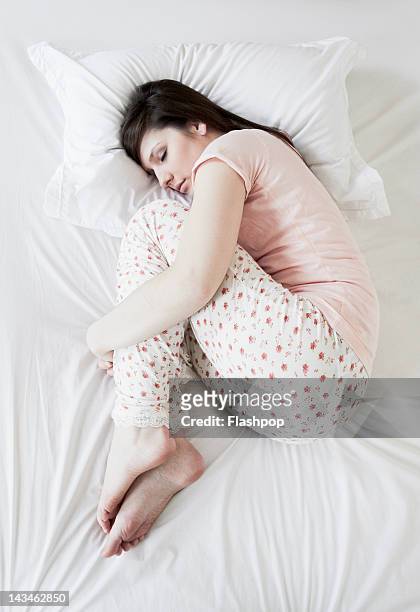 woman sleeping on bed - position du foetus photos et images de collection