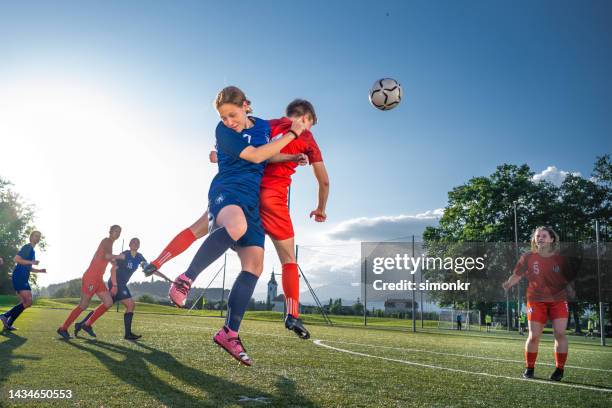 female players heading ball - soccer uniform stockfoto's en -beelden