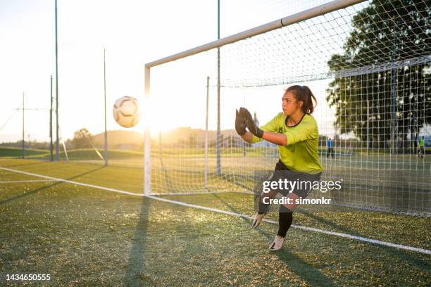 goal keeper jumping to catch football - woman goalie stock pictures, royalty-free photos & images