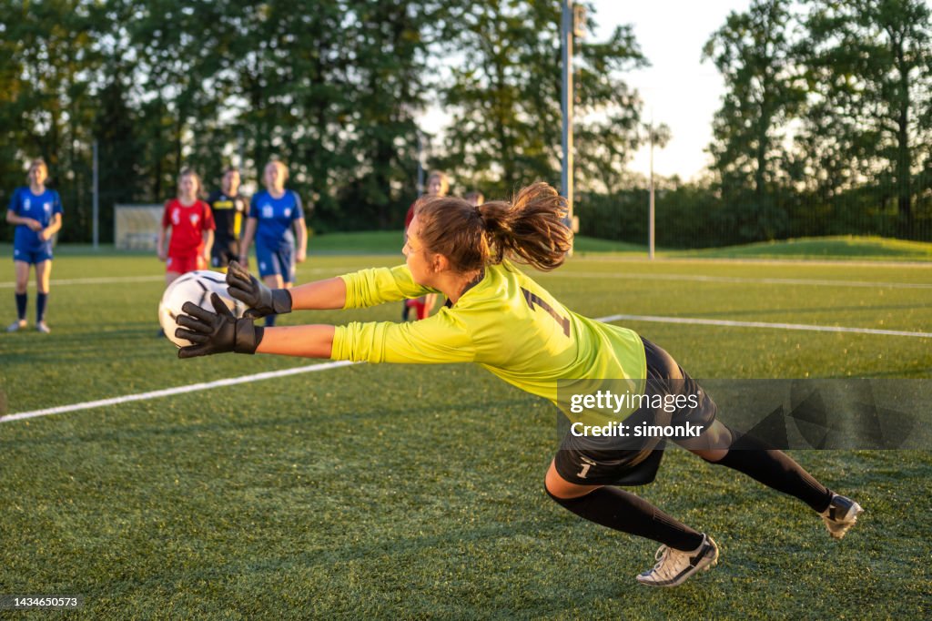 Goal keeper jumping to catch football