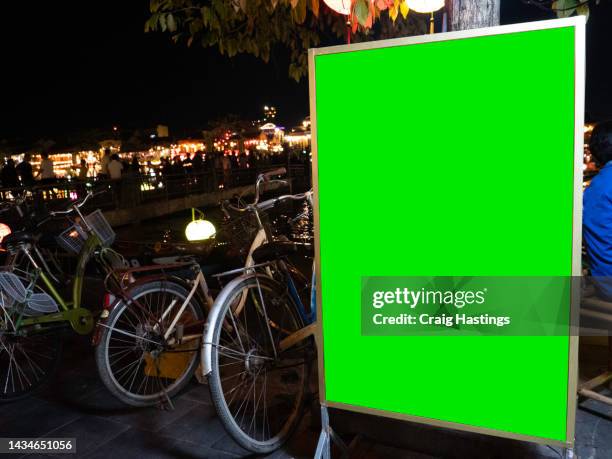 close up large green screen advertisement billboard at hot an river as tourists enjoy the night time restaurants and entertainment. ad space, copy space chroma key, how an, vietnam - vietnam wall stock pictures, royalty-free photos & images