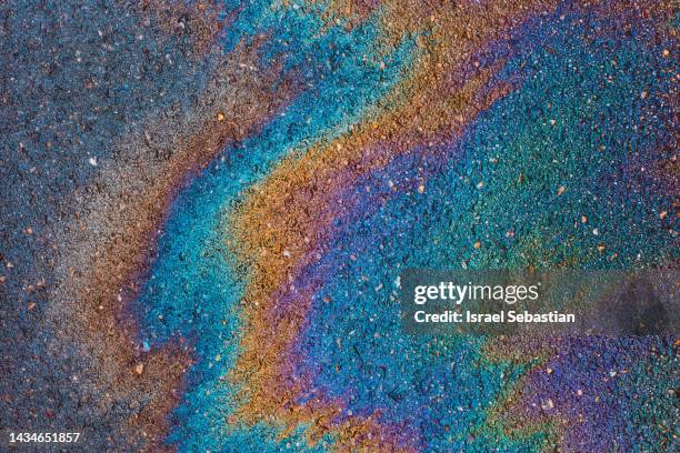 oil leaked from a vehicle onto the road and running due to rainfall. - ölpest stock-fotos und bilder
