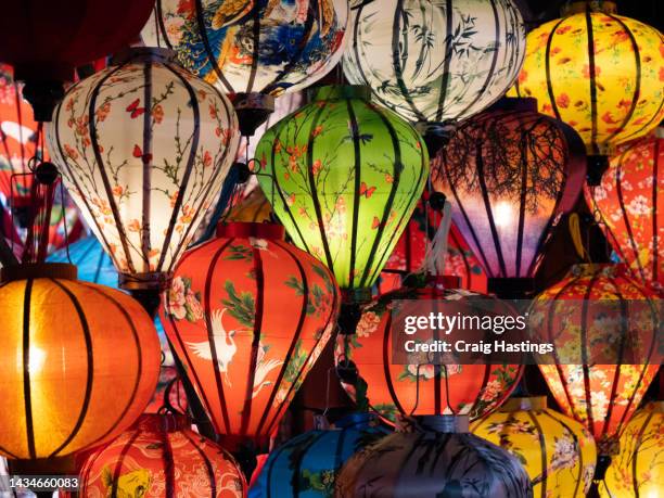 hoi an vietnamese chinese style lanterns of many colours on display on the streets of the city. colourful illuminations for ancient style lamps shine across the street. establishing shot of south east asia tourist area with arts and crafts - ho chi minh city stock pictures, royalty-free photos & images