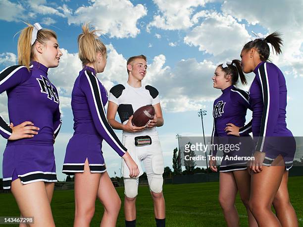 quarterback and cheerleaders talking on field - teen cheerleader stock-fotos und bilder