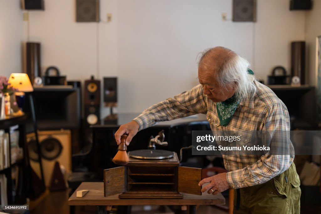 A senior man enjoying analog records in his study.