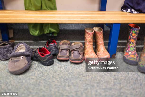 assorted children's shoes under bench - coat check stock pictures, royalty-free photos & images