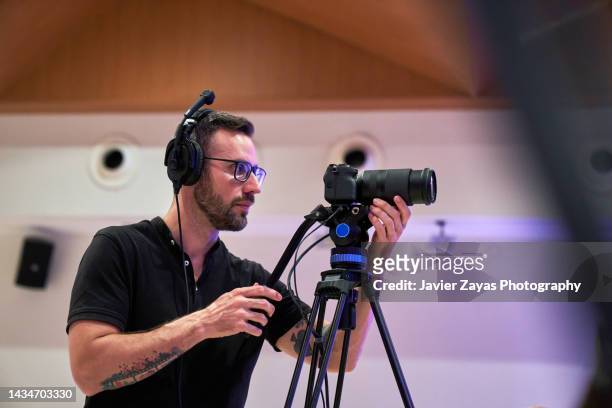cameraman at work using tripod (indoors) - reporterstil stock-fotos und bilder