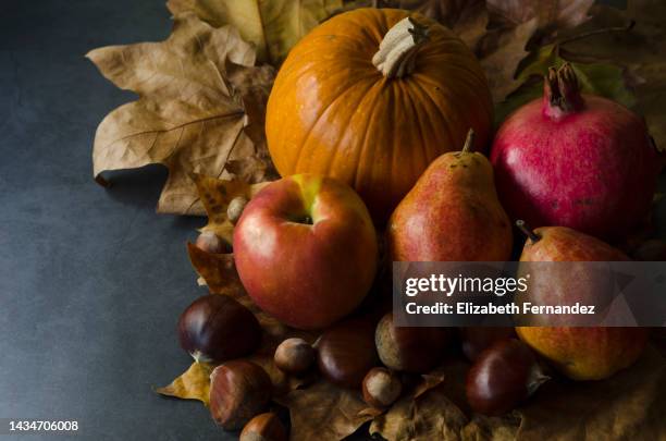 pumpkin and autumn leaves with fruits, chestnuts and hazelnut on black background. harvest time. happy thanksgiving. - brown apple stock pictures, royalty-free photos & images