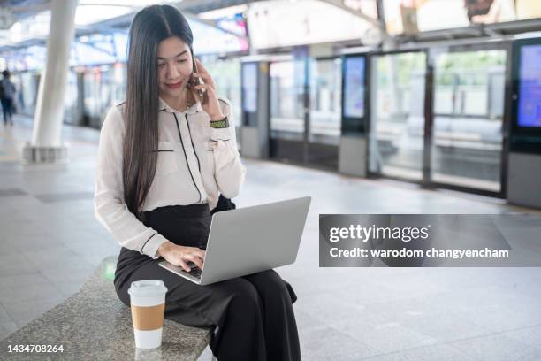 confident asian woman using smartphone and labtop at light rail. - métro léger photos et images de collection