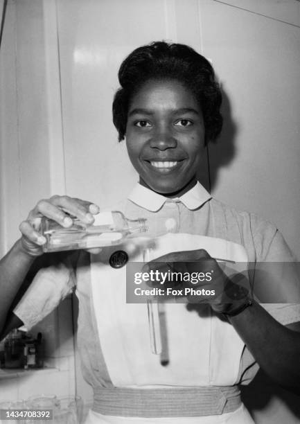 Ghanaian nurse Una Leacock smiles as holds a flask and test tube to make up a prescription in the laboratory after taking up her assistant nurse...