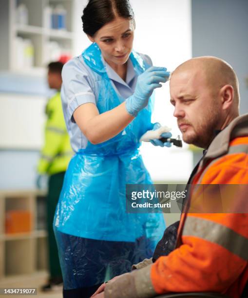 infermiere che pulisce una ferita correlata al lavoro - head injury foto e immagini stock