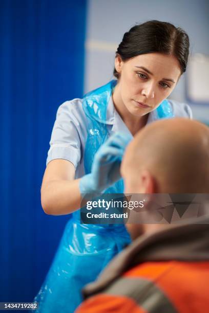 nurse cleaning a work related wound injury - head wound stock pictures, royalty-free photos & images