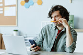 Bored Young Man in Office Using Phone
