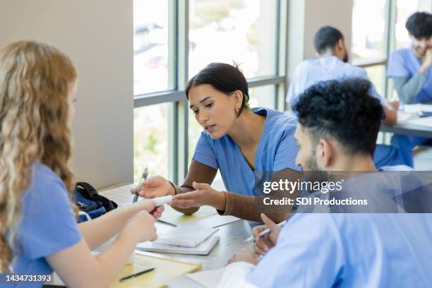 female nursing student looks at friend's bandaged thumb - bandaged thumb stock pictures, royalty-free photos & images