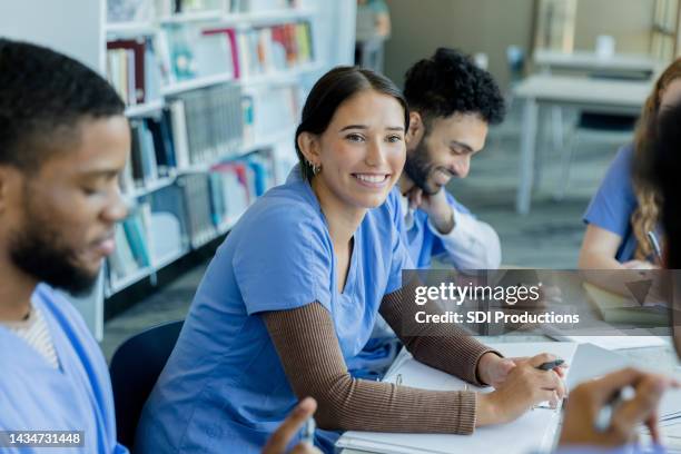 fellow students smile as two classmates discuss ideas - doctor scrubs stock pictures, royalty-free photos & images