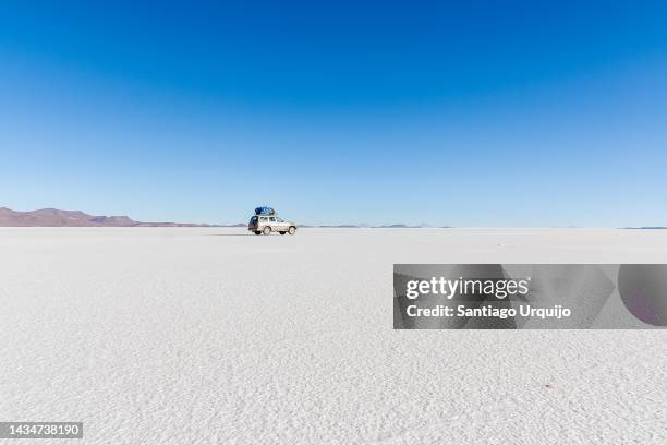 off road vehicle traversing the uyuni salt flats - salt flats stock-fotos und bilder