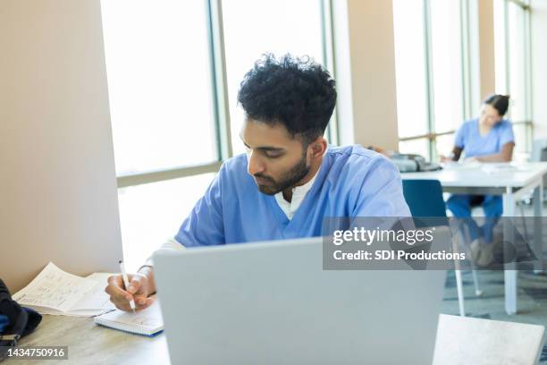 young adult male takes notes - doctor male laptop stock pictures, royalty-free photos & images