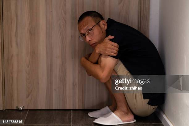 mentally ill man curled up in the corner - madness stock pictures, royalty-free photos & images