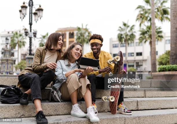 multiracial group sitting around having a good time in the city - spring city break stock pictures, royalty-free photos & images