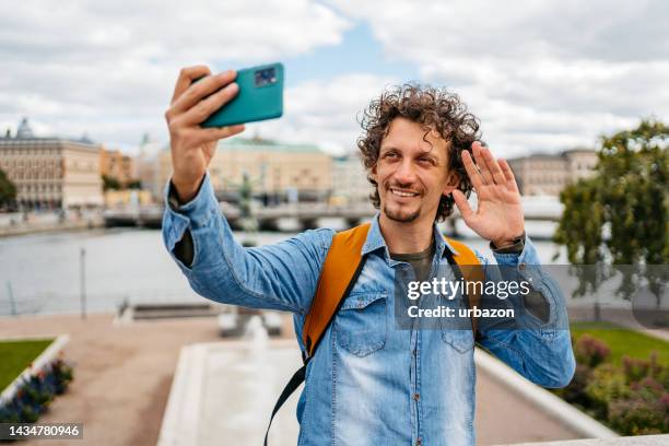 young man having a video call on the quayside - stockholm stock pictures, royalty-free photos & images