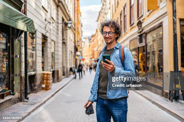 giovane turista che utilizza una mappa su uno smartphone - uomo con smartphone foto e immagini stock