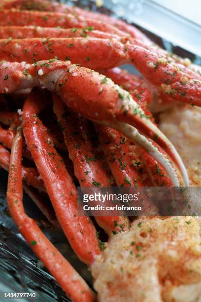 crab legs ready to be baked - macro shot of crab legs - garlic butter and crab seasoning - crab leg stock pictures, royalty-free photos & images