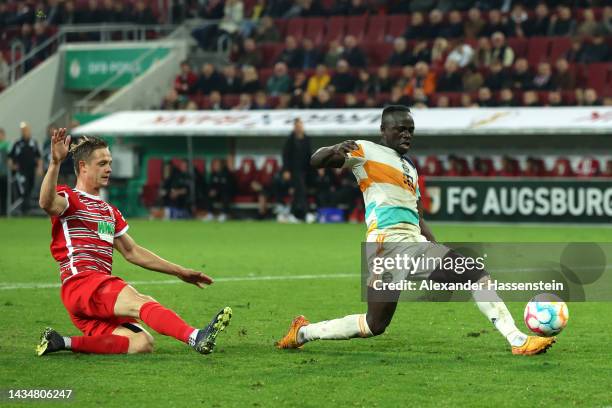 Sadio Mane of Bayern Munich has a shot on goal whilst under pressure from Robert Gumny of FC Augsburg during the DFB Cup second round match between...