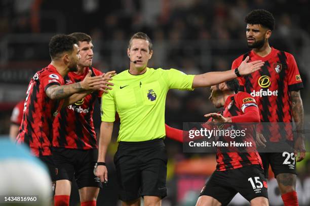 Referee John Brooks is confronted by players of AFC Bournemouth as they plead for a penalty following a potential hand ball incident during the...