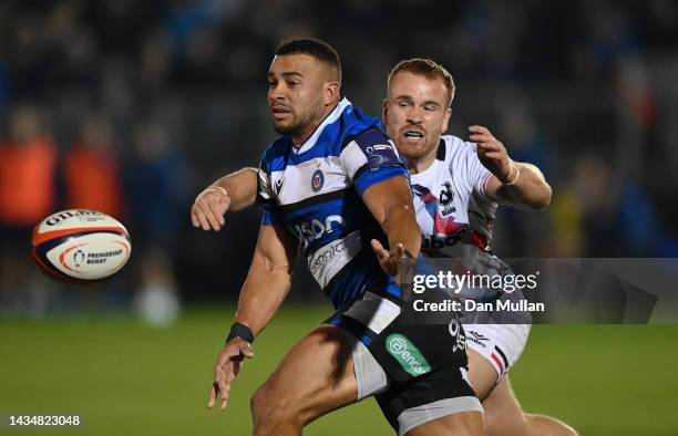 Jonathan Joseph of Bath offloads under pressure from James Williams of Bristol Bears during the Premiership Rugby Cup match between Bath Rugby and...