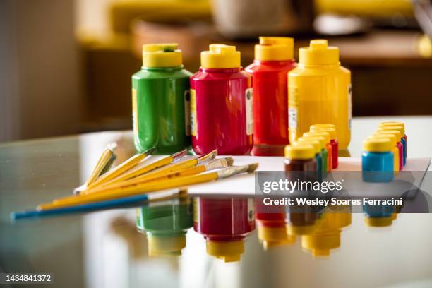 close up of a gouache paint pots and brushes over a white paper reflecting on a glass table - gouache stock pictures, royalty-free photos & images