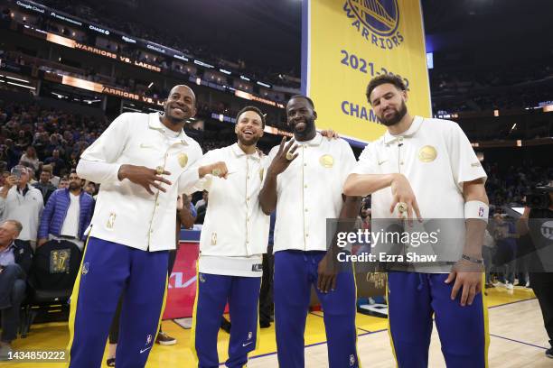 Andre Iguodala, Stephen Curry, Draymond Green, and Klay Thompson of the Golden State Warriors pose with their championship rings in front of a...