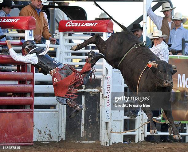 Chon Miranda grabs the rail as he flies off Goodtimes during the 98th Annual Clovis Rodeo in Clovis, California, on Thursday, April 26, 2012.