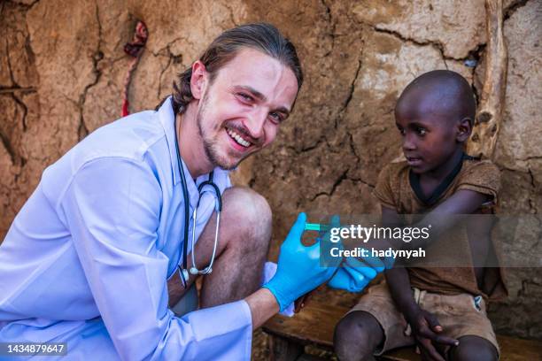 arzt macht eine injektion an kleinen afrikanischen jungen in kleinem dorf, kenia - doctors without borders stock-fotos und bilder