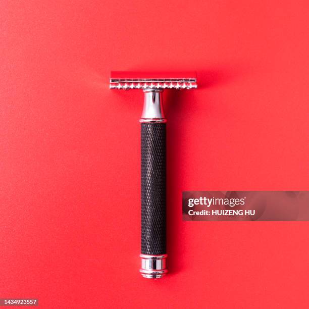 razor black color for men on red background - safety shave razor stock-fotos und bilder