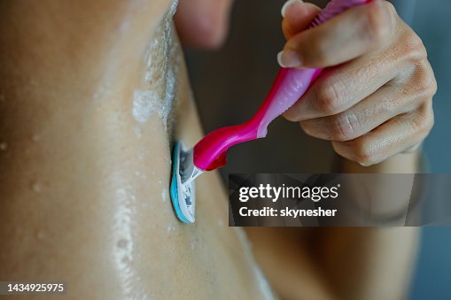 Close up of unrecognizable woman shaving her armpit under the shower. Close up of unrecognizable woman shaving her armpit under the shower.