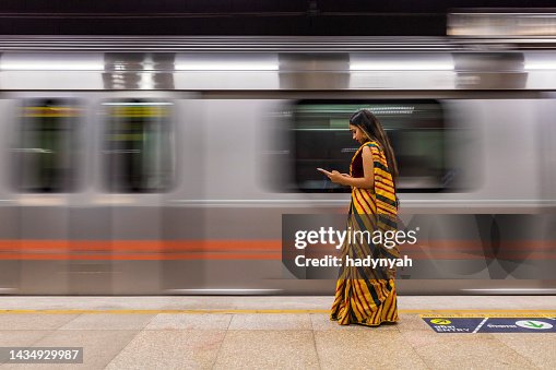 Indian girl using a digital tablet at metro station, India Indian girl using a digital tablet at metro station, India