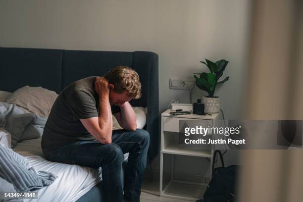 mature male sitting on his bed - negative emotion - depressie stockfoto's en -beelden