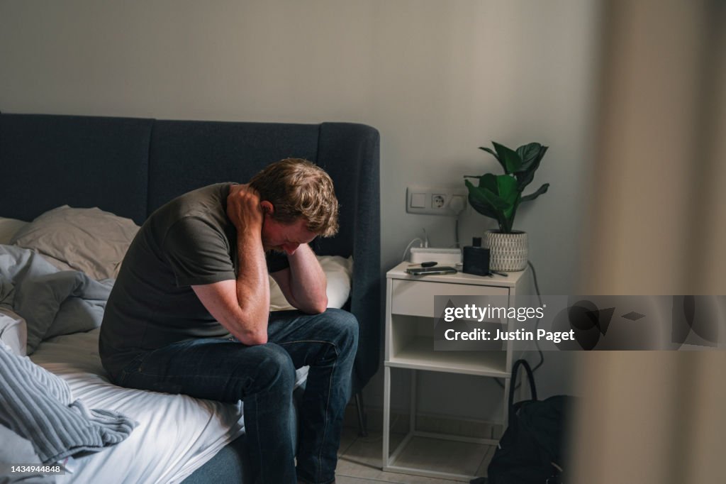 Mature male sitting on his bed - negative emotion