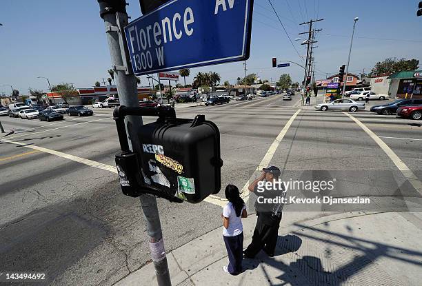 Pedestrians wait as a funeral procession passes through the intersection of Florence and Normandy Avenues in South Los Angeles on April 27, 2012 in...