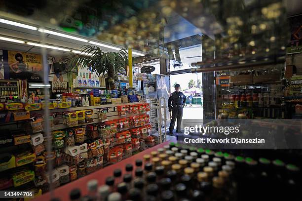 Security officer inside keeps watch at the entrance of Tom Liquor store at the intersection of Florence and Normandy in South Los Angeles on April...